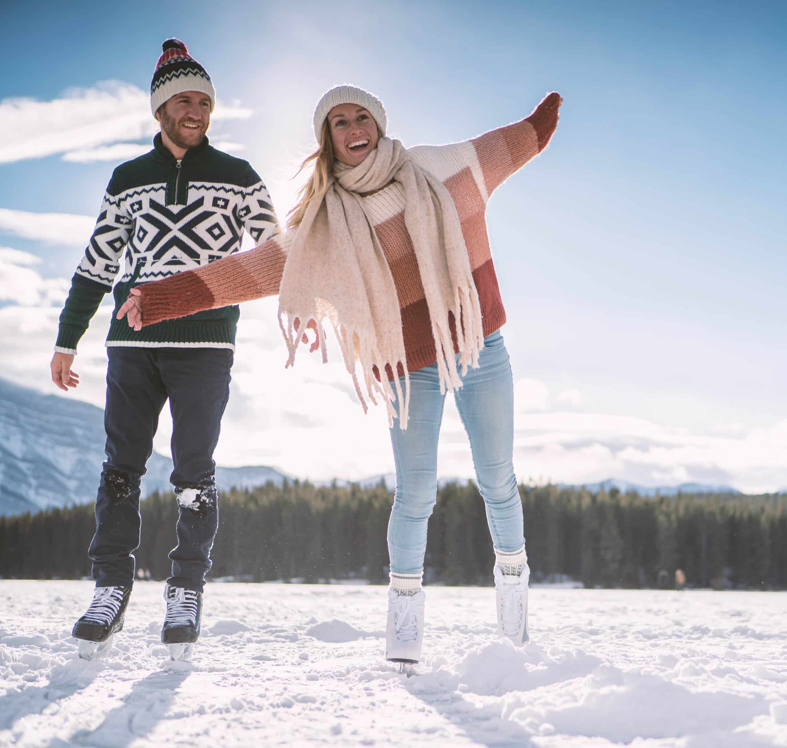 Paarferien in St. Moritz 9 Happy young couple ice skating hand in hand on frozen lake enjoying winter fun